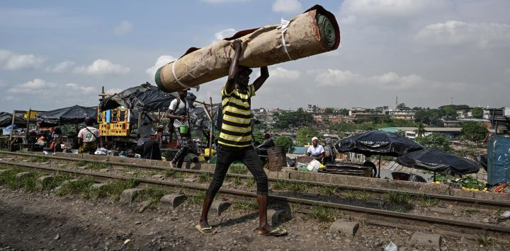Un portaequipajes camina junto a la vía férrea en Adjame, comuna urbana de Abiyán, Costa de Marfil.