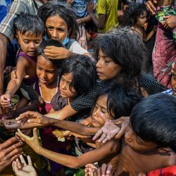 Los refugiados rohingya recién llegados reciben alimentos donados por personas en una playa en Laweueng, distrito de Pidie en la provincia indonesia de Aceh. Más de 300 refugiados rohingya, en su mayoría mujeres y niños, quedaron varados en las costas del oeste de Indonesia. | Foto:CHAIDEER MAHYUDDIN / AFP