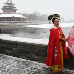 Una mujer posa para fotografías con un traje imperial junto al foso que rodea la Ciudad Prohibida, durante una nevada en Beijing, China. | Foto:GREG BAKER / AFP