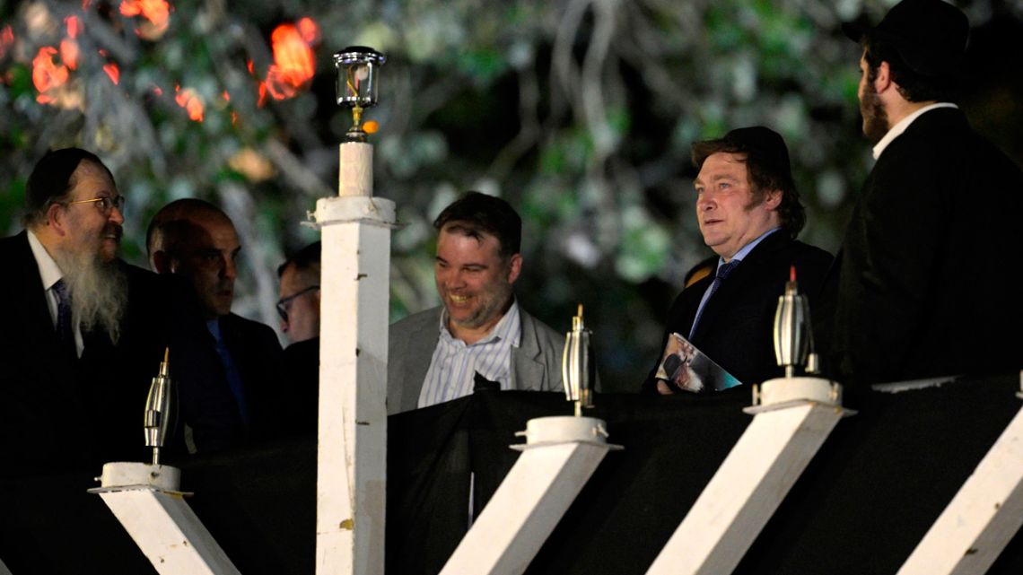 Rabbi Tzvi Grunblatt (left) and Argentina's President Javier Milei (second right) gesture before lighting the giant Menorah candelabrum, set up for the traditional Jewish Hanukkah (Chanukah) Festival of Lights in Buenos Aires on December 12, 2023. 