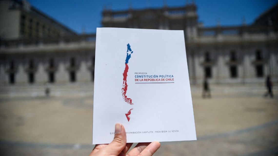 A man holds a copy of Chile's proposed new Constitution in front of La Moneda Presidential Palace in Santiago on December 12, 2023. 