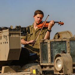 La fotografía tomada en el sur de Israel, cerca de la frontera con la Franja de Gaza, muestra a un soldado israelí tocando el violín en un tanque, en medio de continuas batallas entre Israel y el grupo militante Hamás. | Foto:MENAHEM KAHANA / AFP