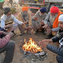 La gente se sienta alrededor de una hoguera en un frío día de invierno en las afueras de Amritsar, India. | Foto:Narinder Nanu / AFP