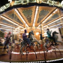 Los niños se sientan en los caballos de madera de un carrusel en un mercado navideño en Piazza Navona en Roma, Italia. | Foto:ANDREAS SOLARO / AFP