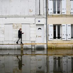 Una mujer camina sobre un puente de madera instalado en las calles mientras el río Charente inundaba la ciudad de Saintes, en el suroeste de Francia. | Foto:CHRISTOPHE ARCHAMBAULT / AFP