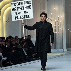Un modelo sostiene un cartel que pide la paz mientras presenta una creación del diseñador de moda Emraan Rjput durante la Semana de Alta Costura Nupcial Pantene HUM, en Lahore, Pakistán. | Foto:ARIF ALI / AFP