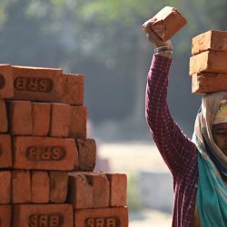 Un trabajador carga ladrillos de arcilla sobre su cabeza en una obra de construcción en Nueva Delhi, India. | Foto:Sajjad Hussain / AFP