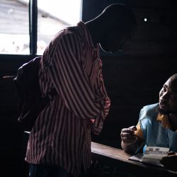 Un funcionario de la Comisión Electoral Nacional Independiente ayuda a un votante en un colegio electoral del Institut Ndahura en Goma. Millones de congoleños acuden a las urnas en unas elecciones generales marcadas por graves problemas logísticos que provocaron que algunos colegios electorales nunca abrieran. | Foto:ALEXIS HUGUET / AFP