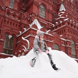 Un niño se sienta sobre un montón de nieve en la Plaza Roja cubierta de nieve de Moscú. | Foto:NATALIA KOLESNIKOVA / AFP