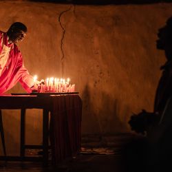 Un sacerdote de la Misión de la Iglesia Africana Legio María enciende velas durante la misa de vigilia de Nochebuena en una iglesia cerca de Ugunja, Kenia. | Foto:LUIS TATO/AFP
