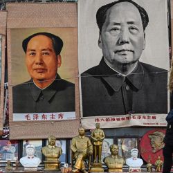 Una mujer pasa junto a imágenes que representan al difunto líder comunista chino Mao Zedong en un puesto en un mercado de antigüedades en Beijing, el 130 aniversario del nacimiento del padre fundador de la China comunista. | Foto:Jade Gao / AFP