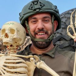Una fotografía tomada en el sur de Israel, en la frontera con Gaza, muestra a un soldado israelí posando para una fotografía con un esqueleto de plástico encontrado durante las operaciones militares en la Franja de Gaza, en medio de las batallas en curso entre Israel y el grupo militante palestino Hamás. | Foto:JACK GUEZ / AFP