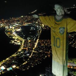 Vista aérea que muestra una imagen proyectada sobre la estatua del Cristo Redentor que rinde homenaje a la leyenda del fútbol brasileño Pelé en el primer aniversario de su muerte, en el Monte Corcovado en Río de Janeiro, Brasil. | Foto:MAURO PIMENTEL / AFP