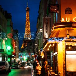 Esta fotografía muestra a personas paradas afuera de un restaurante con la Torre Eiffel iluminada de fondo en París. | Foto:DIMITAR DILKOFF / AFP