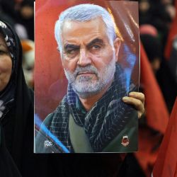 Una mujer iraní sostiene un retrato del alto comandante iraní asesinado Qasem Soleimani durante la ceremonia de conmemoración del aniversario de su asesinato en la capital iraní, Teherán. | Foto:ATTA KENARE / AFP