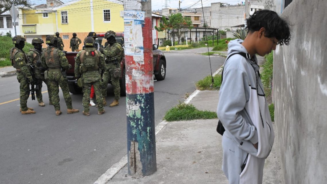 Members of the military frisk a man (L) while another remains facing a wall during a patrol in the streets of Quito on January 11 as Ecuador is in a "state of emergency."