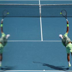 El argentino Francisco Cerundolo sirve contra el australiano Dane Sweeny mientras se ve su reflejo durante su partido individual masculino el primer día del torneo de tenis Abierto de Australia en Melbourne. | Foto:MARTIN KEEP / AFP