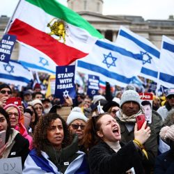 Los partidarios proisraelíes ondean banderas israelíes e iraníes anteriores a la revolución mientras se reúnen para una manifestación en Trafalgar Square, en el centro de Londres, para mostrar apoyo a las familias en duelo, las familias de rehenes, los soldados y el pueblo de Israel. | Foto:HENRY NICHOLLS / AFP