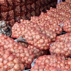 Un trabajador transporta un saco de cebollas descargadas de un camión en un mercado de verduras en Lahore, Pakistán. | Foto:ARIF ALI / AFP