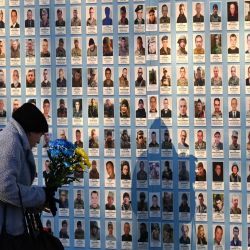 Una mujer deposita flores con los colores de la bandera ucraniana en el Muro del Recuerdo de los Defensores Caídos de Ucrania en la Guerra Ruso-Ucraniana, en Kiev, en medio de la invasión rusa en Ucrania. | Foto:SERGEI SUPINSKY / AFP