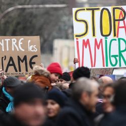 Los manifestantes sostienen carteles que dicen "Contra los asesinos del AME" y "Alto a la ley de inmigración" mientras participan en una manifestación contra la ley de inmigración recientemente adoptada por Francia, en París. | Foto:Guillaume Baptiste / AFP