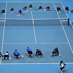 El personal y los voluntarios ayudan a secar la cancha durante el partido individual femenino entre la estadounidense Amanda Anisimova y la bielorrusa Aryna Sabalenka en el octavo día del torneo de tenis del Abierto de Australia en Melbourne. | Foto:Paul Crock / AFP