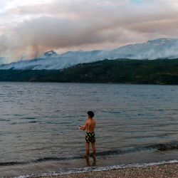 Un turista pesca en el lago Futalaufquen mientras se ve el humo de un incendio forestal en el Parque Nacional Los Alerces en la provincia de Chubut, Argentina. Foto de MARTIN LEVICOY / AFP | Foto:AFP