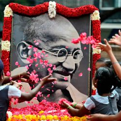 Los niños de las escuelas indias arrojan pétalos de rosas sobre un retrato de Mahatma Gandhi para rendir homenaje en el aniversario de la muerte del padre fundador de la India. Foto de R. Satish BABU / AFP | Foto:AFP