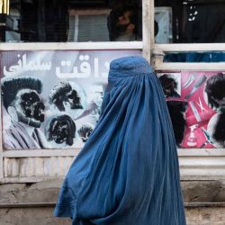 Una mujer afgana vestida con burka pasa junto a una barbería con imágenes de hombres desfiguradas en la zona de Koch-e Sang Tarashi de Kabul. Foto de Wakil KOHSAR / AFP | Foto:AFP