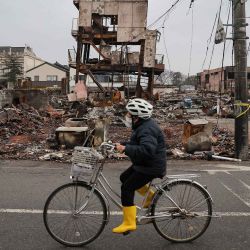 Una persona pasa en bicicleta entre los escombros de edificios destruidos por un incendio en la popular zona de Asaichi Dori en la ciudad de Wajima, después de un terremoto. Foto de JIJI Press / AFP | Foto:AFP