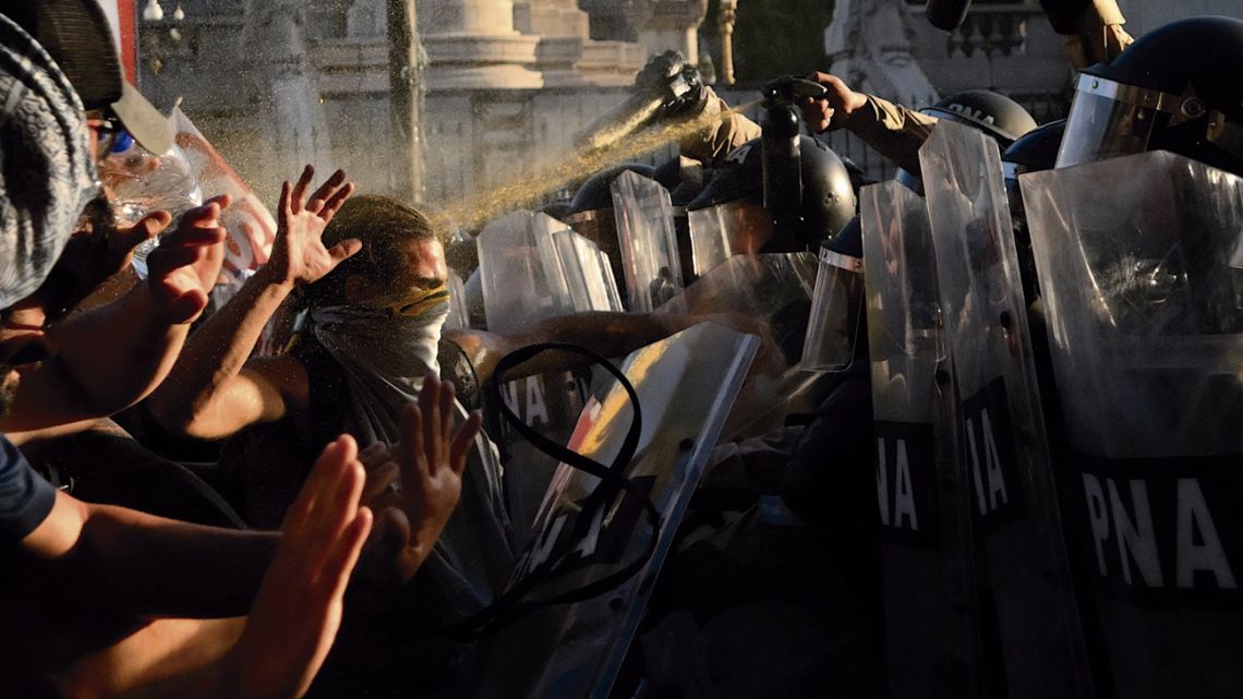 A protester is hit with tear gas by security forces amid demonstrations outside Congress.