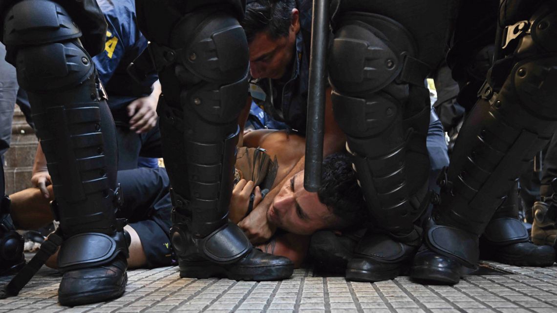 Riot police detain a protester during a protest outside the National Congress building.