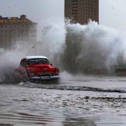 Un viejo auto estadounidense pasa por el malecón inundado debido a un frente frío en La Habana, Cuba. Foto de YAMIL LAGE / AFP | Foto:AFP