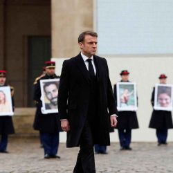 El presidente francés, Emmanuel Macron, camina delante de miembros de la Guardia Republicana francesa que muestra retratos de los 42 ciudadanos franceses y franco-israelíes asesinados. Foto GONZALO FUENTES / AFP | Foto:AFP
