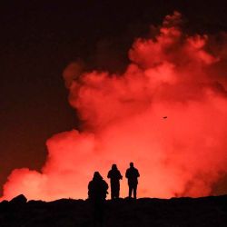 Un grupo de personas observa lava fundida y humo que sale de una fisura durante una erupción volcánica cerca de Grindavik, en el oeste de Islandia. Foto de Kristinn Magnusson / AFP | Foto:AFP