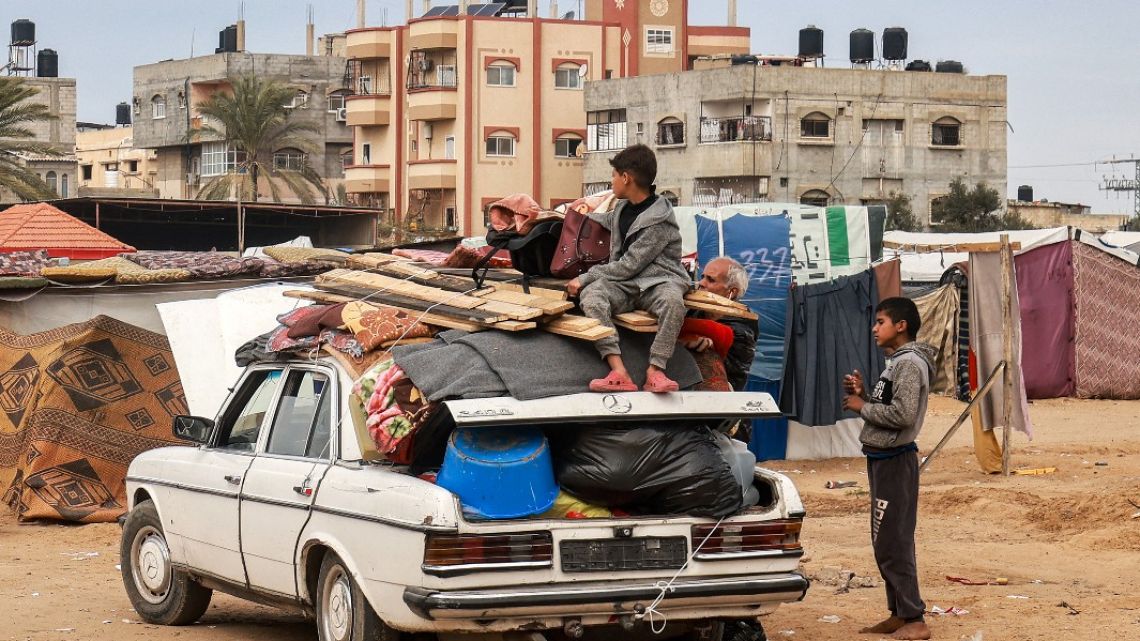 A child sits atop items secured onto a vehicle by rope as people flee from Rafah in the southern Gaza Strip on February 13, 2024.