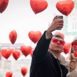 Una pareja se toma una foto bajo globos en forma de corazón exhibidos el día de San Valentín en el centro de Moscú. Foto de Natalia KOLESNIKOVA / AFP  | Foto:AFP