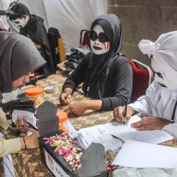 Un miembro del personal vestido con un disfraz de terror ayuda a un votante en un colegio electoral durante las elecciones presidenciales y legislativas de Indonesia en Surabaya. Foto de Surya Putra / AFP | Foto:AFP