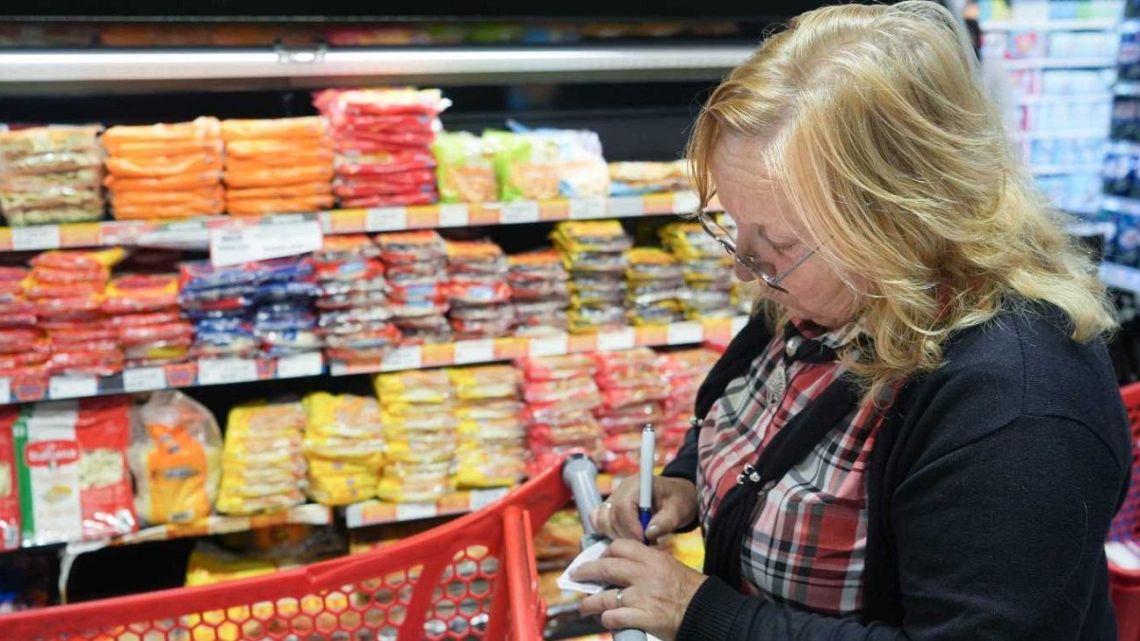 A shopper checks prices at a supermarket in Buenos Aires.
