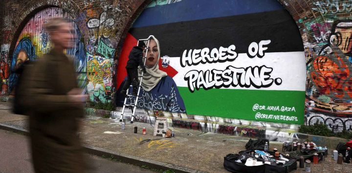 Un artista de graffiti trabajando para crear una imagen de arte callejero de la Dra. Haya Hijazi, una doctora en Gaza. Londres. Foto de Daniel LEAL / AFP