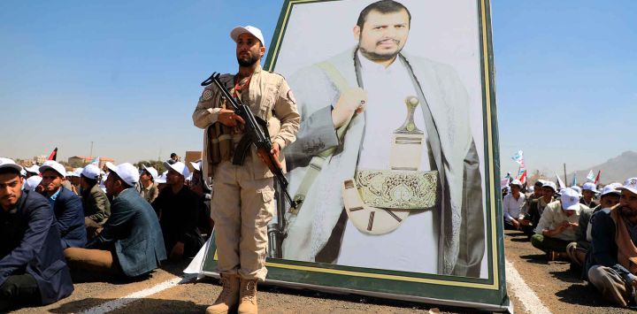 Un guardia de seguridad hutí frente a un retrato del líder del grupo yemení, Abdul Malik al-Huthi, mientras estudiantes reclutados participan en una manifestación contra EE UU, Gran Bretaña e Israel. Foto de MOHAMMED HUWAIS / AFP