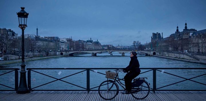 Una mujer anda en bicicleta por el puente Pont des Arts sobre el río Sena, en París. Foto de Kiran RIDLEY / AFP  