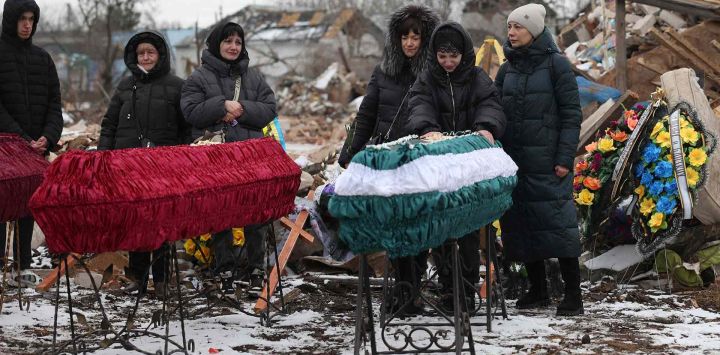 Familiares y amigos asisten a una ceremonia fúnebre de una familia en su casa que fué destruida por un ataque con misiles rusos, en Kramatorsk. Foto de Anatolii STEPANOV / AFP