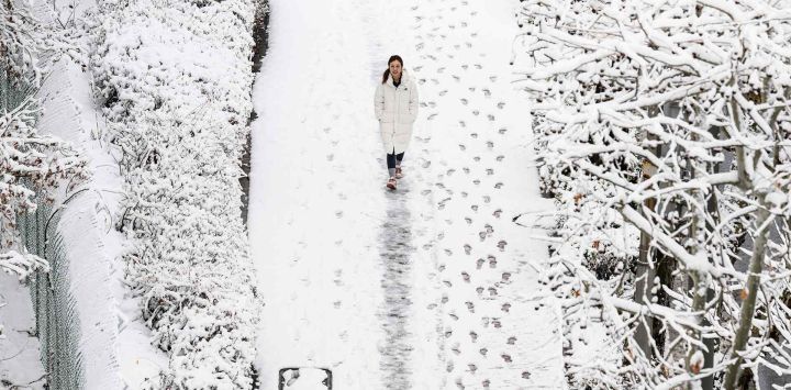 Una mujer camina por un sendero después de una nevada en Seúl. Foto de ANTHONY WALLACE / AFP 
