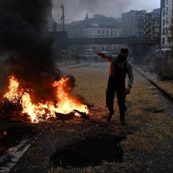 Un manifestante se encuentra junto a la quema de heno y neumáticos durante una protesta convocada por las organizaciones de agricultores "Federation Unie de Groupements d'Eleveurs et d'Agriculteurs" (FUGEA), Boerenforum y MAP, en respuesta al Consejo Europeo de Agricultura, en Bruselas. | Foto:JOHN THYS / AFP