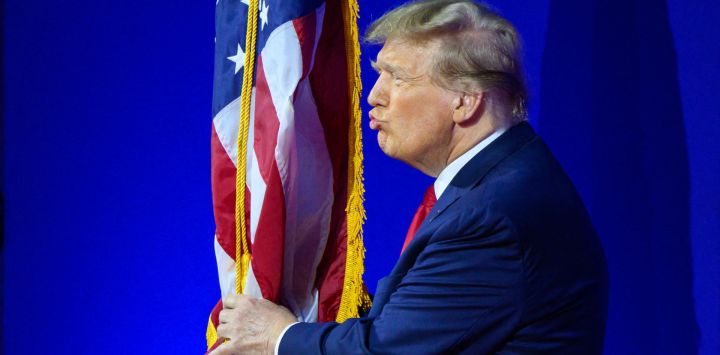 El ex presidente de Estados Unidos y aspirante a la presidencia de 2024, Donald Trump, besa la bandera de Estados Unidos cuando llega para hablar durante la reunión anual de la Conferencia de Acción Política Conservadora (CPAC), en National Harbor, Maryland.