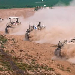 Esta fotografía tomada desde Israel cerca de la frontera con la Franja de Gaza muestra vehículos blindados de transporte de personal israelíes saliendo de Gaza, en medio de las batallas en curso entre Israel y el grupo militante palestino Hamás. | Foto:MENAHEM KAHANA / AFP