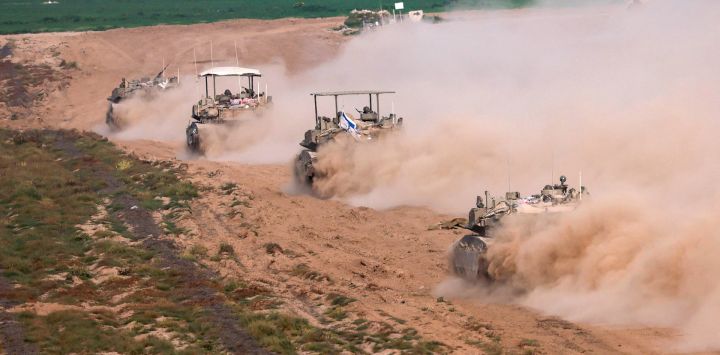 Esta fotografía tomada desde Israel cerca de la frontera con la Franja de Gaza muestra vehículos blindados de transporte de personal israelíes saliendo de Gaza, en medio de las batallas en curso entre Israel y el grupo militante palestino Hamás.