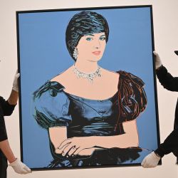 El "Retrato de la princesa Diana" del artista estadounidense Andy Warhol, creado a partir de polímero sintético y tinta de serigrafía sobre lienzo, valorado en 1.200 libras esterlinas (1.400 euros, 1.500 dólares), lo exhiben los asistentes de la galería durante una sesión fotográfica antes de la subasta de arte contemporáneo y del siglo XX. en la casa de subastas Phillips en Londres. | Foto:JUSTIN TALLIS / AFP