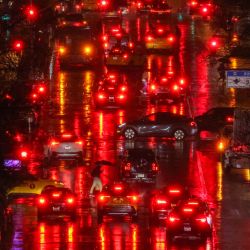 Peatones y automóviles avanzan por la Primera Avenida en el distrito de Manhattan de Nueva York, bajo la lluvia torrencial. | Foto:CHARLY TRIBALLEAU / AFP